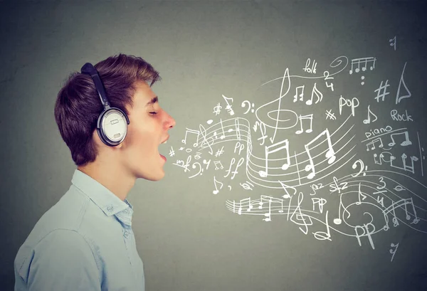 Jeune homme chantant avec des notes de musique sortant de la bouche — Photo