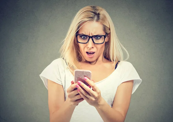 Шокированная женщина смотрит на мобильный телефон — стоковое фото
