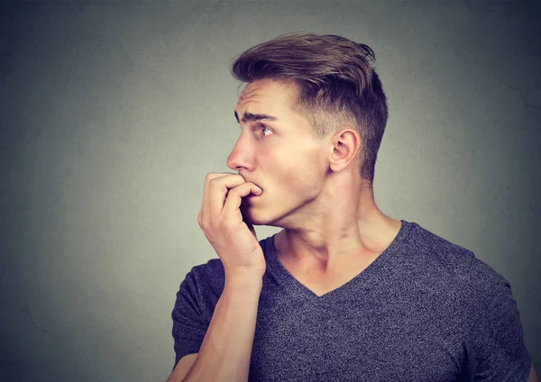 Preoccupato ansioso giovane uomo che si morde le unghie guardando di lato — Foto Stock