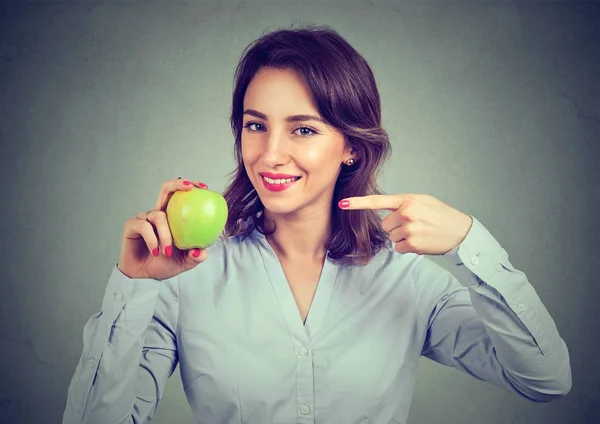 Щаслива молода жінка тримає вказівник на зелене яблуко — стокове фото