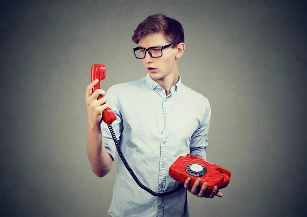 Verwirrter Teenager schaut auf altmodisches Telefon — Stockfoto