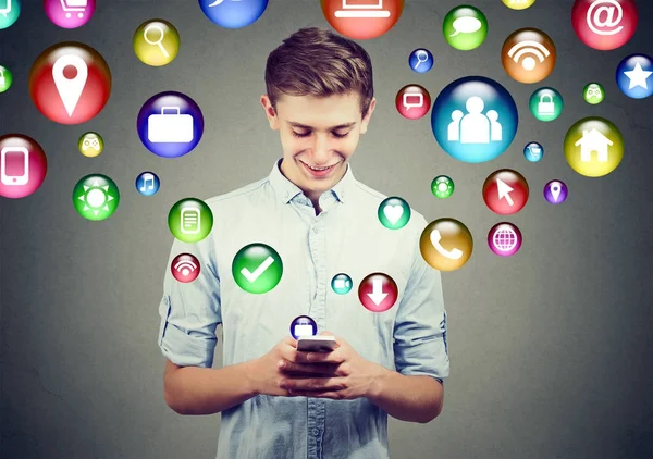 Hightech-Konzept für mobile Technologie. Glücklicher junger Mann nutzt Smartphone mit Social-Media-App-Icons, die aus dem Bildschirm fliegen — Stockfoto
