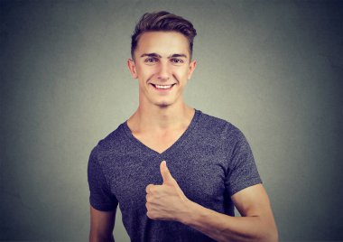 Başparmak gösterilmesini mutlu yakışıklı genç 