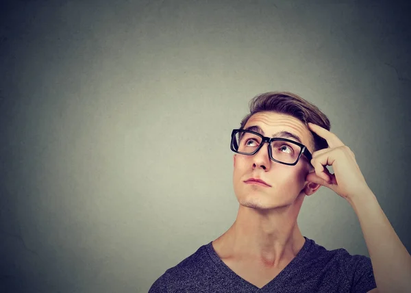 Вдумливий молодий чоловік в окулярах стоїть біля стіни — стокове фото