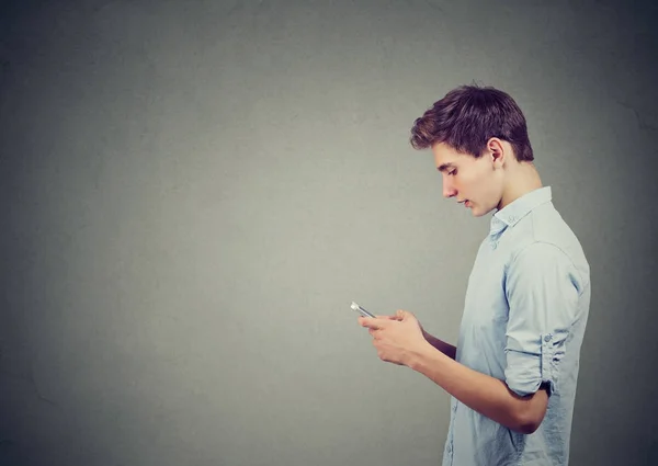Yakışıklı bir genç adam bir smartphone kullanarak yan profili — Stok fotoğraf