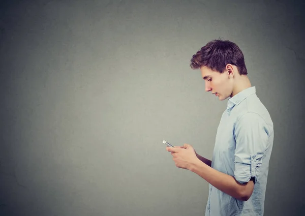 Perfil lateral de un joven guapo usando un teléfono inteligente — Foto de Stock