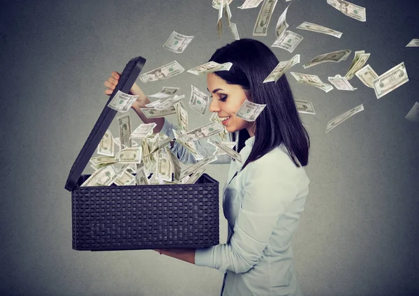 Happy woman opening a box with money flying out away — Stock Photo, Image