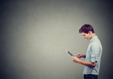 Mavi gömlekli yakışıklı adam dijital tablet kullanma ve gülümseyen 