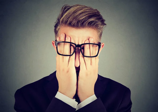 Closeup portrait young man in glasses covering face eyes with both hands — Stock Photo, Image