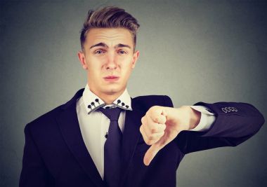 Başparmak aşağı işaret, uygun görmeme onaylamama içinde gösterilen kızgın hayal kırıklığına uğramış genç iş adamı 