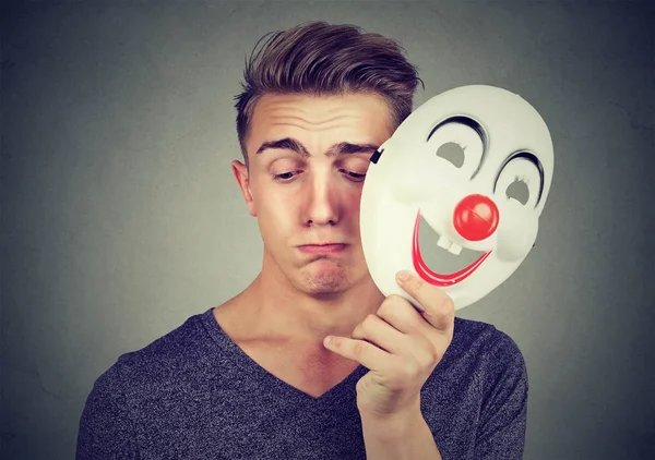 Trieste jongeman happy clown masker opstijgen. Menselijke emoties. — Stockfoto