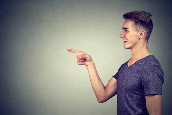 Profil boczny roześmiany młody człowiek palca wskazującego na kogoś — Zdjęcie stockowe