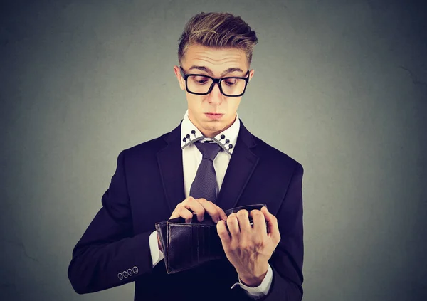 Triste joven hombre de negocios preocupado mirando en su cartera sin dinero —  Fotos de Stock