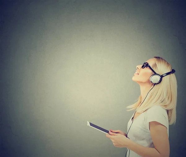 Hermosa mujer feliz con auriculares escuchando música en la tableta —  Fotos de Stock