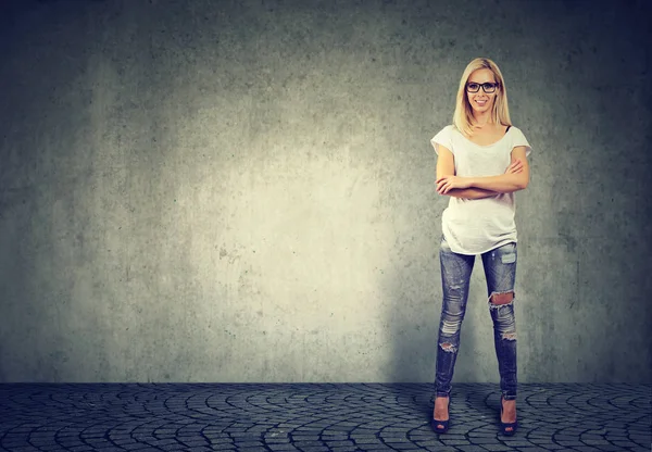 Young confident happy woman standing by concrete wall — Stock Photo, Image