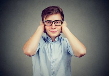 Kulakları kapsayan mutlu yakışıklı genç. Kötü fikir duymak