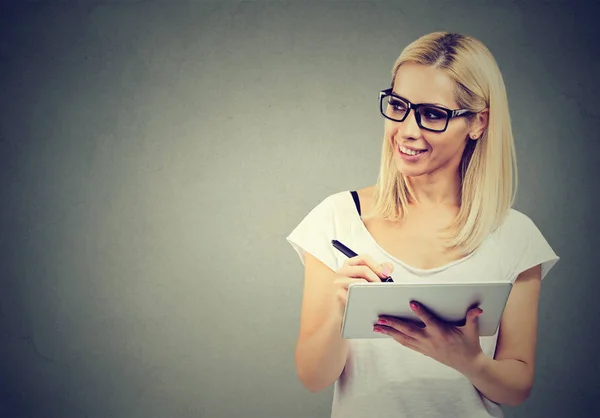 Happy young woman with tablet computer writing and idea, brainstorming looking to the side — Stock Photo, Image