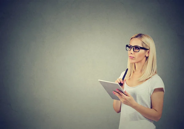 Thoughtful young woman in glasses with tablet computer planning — Stock Photo, Image