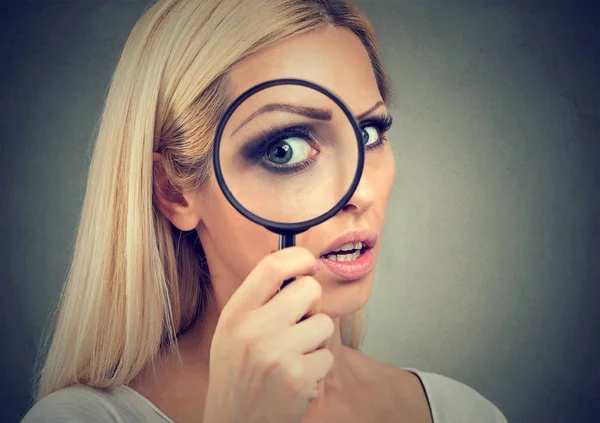 Curious young woman looking through a magnifying glass — Stock Photo, Image