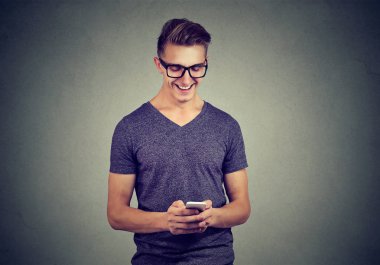 Yakışıklı mutlu genç adam gözlüklü bir smartphone kullanarak