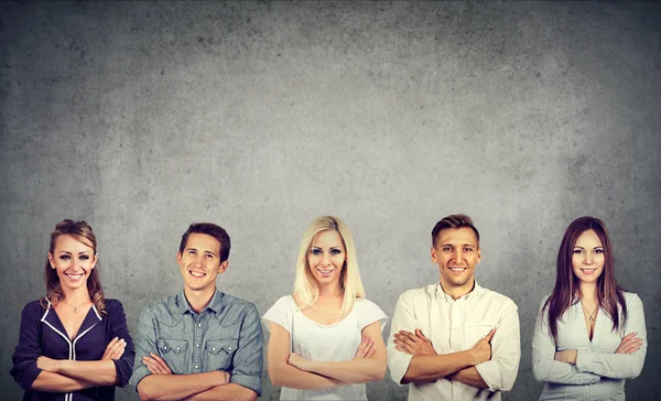 Group of confident people men and women standing along concrete gray wall