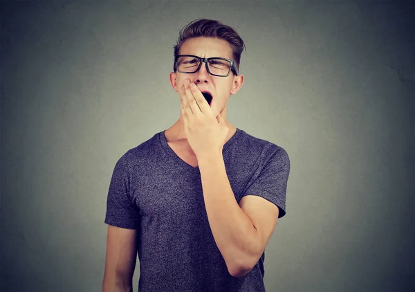 Junger Mann gähnt mit der Hand über dem Mund — Stockfoto