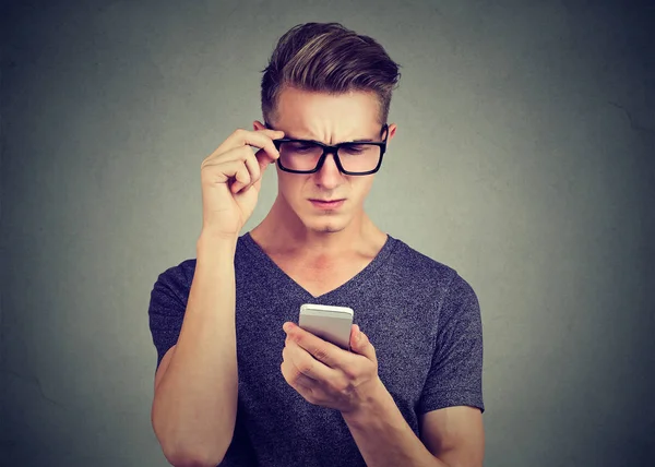 Homme portant des lunettes ayant du mal à voir téléphone cellulaire a des problèmes de vision . — Photo