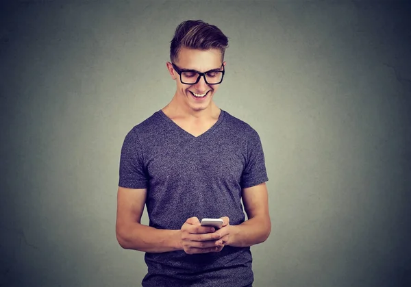 Przystojny szczęśliwy młody facet w okularach za pomocą smartfona — Zdjęcie stockowe