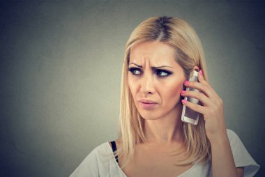 Gri bir arka plan üzerinde onu cep telefonuyla konuşmak güzel kızgın kadın