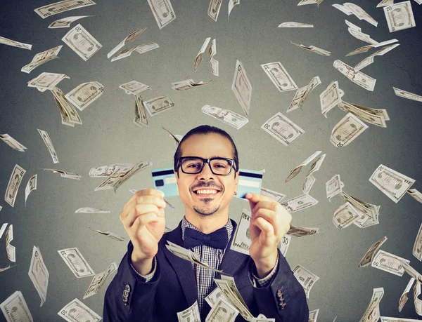 Ευτυχισμένος χρέος δωρεάν νέος άνθρωπος που κρατά μια πιστωτική κάρτα, κομμένα στα δύο υπό βροχή χρημάτων — Φωτογραφία Αρχείου