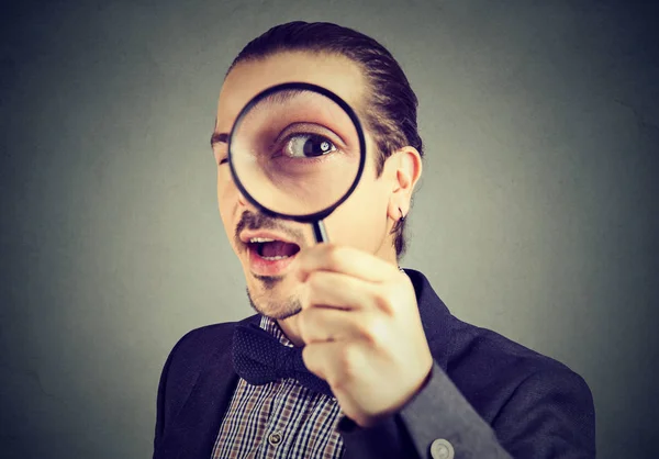 Curious young business man looking through a magnifying glass Stock Photo