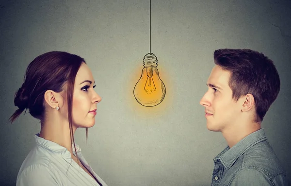 Концепція когнітивних здібностей чоловіків проти жінок. Чоловік і жінка дивляться на яскраву лампочку — стокове фото