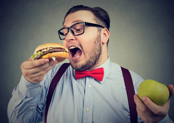 Hombre eligiendo hamburguesa en lugar de manzana —  Fotos de Stock