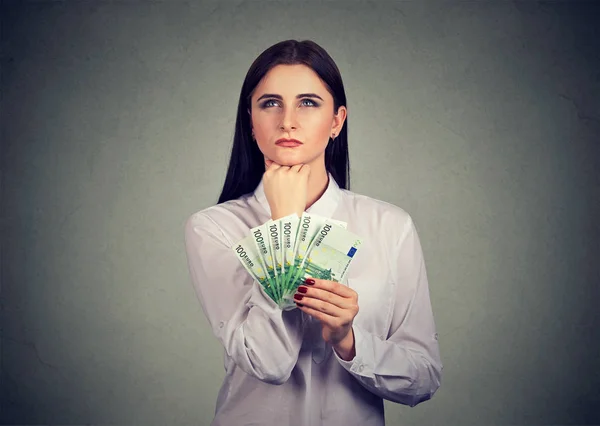 Mulher com dinheiro decidindo sobre gastos — Fotografia de Stock