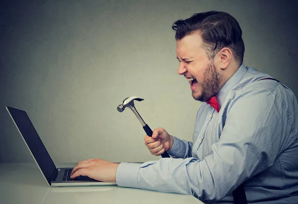 Homem irritado com martelo e laptop quebrado — Fotografia de Stock