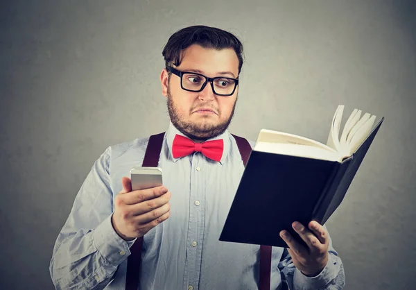 Homem confuso confundido com livro e telefone — Fotografia de Stock