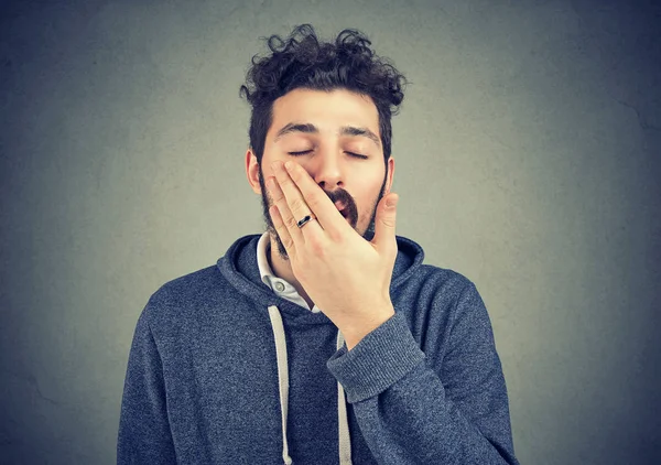Gähnender junger Mann bedeckt Mund — Stockfoto