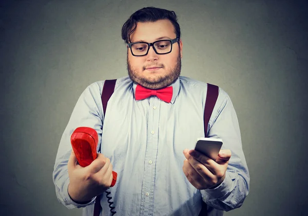 Hombre confundido con teléfonos viejos y nuevos — Foto de Stock