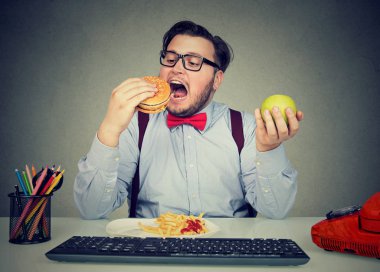 Obese employee eating fast food at workplace clipart