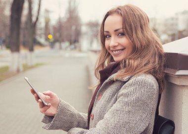 Sevimli genç kadın ile smartphone Caddesi üzerinde