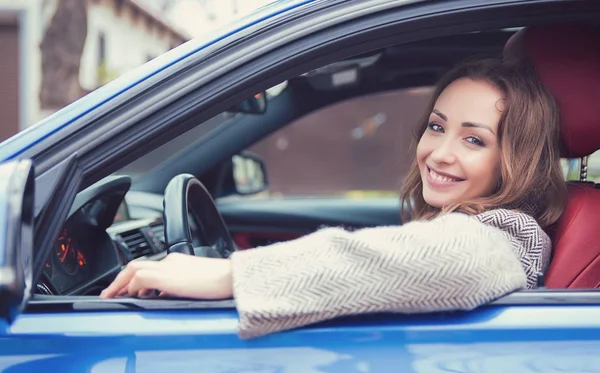 Красивая девушка за рулем машины улыбается в камеру — стоковое фото