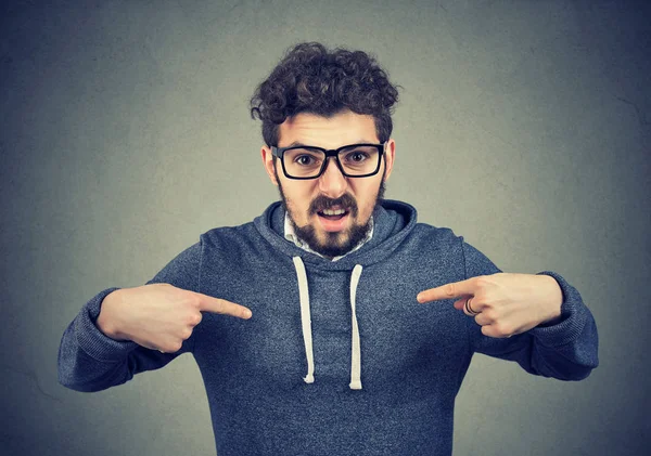 Сердитий чоловік в окулярах занадто реагує, вказуючи на себе — стокове фото