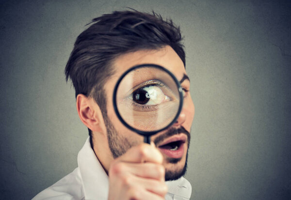 Curious man looking through a magnifying glass 