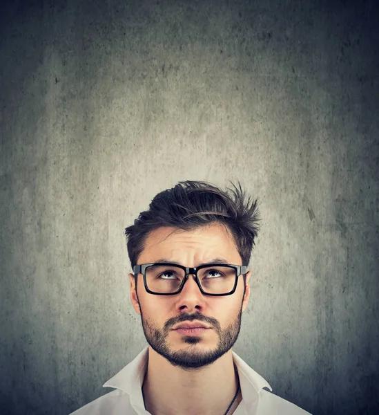 Retrato de un hombre dudoso con gafas mirando hacia arriba —  Fotos de Stock