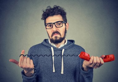 Eski moda kırmızı cep telefonu tutan karışıklık ile kameraya bakan tiksinti adam. 