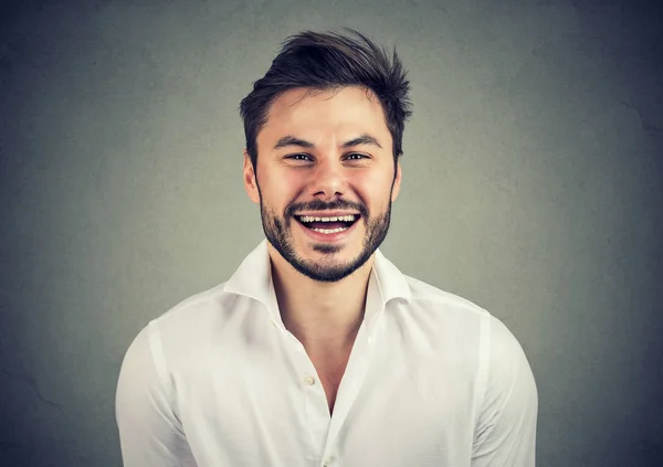 Lachender gutaussehender Mann schaut in die Kamera in grau — Stockfoto