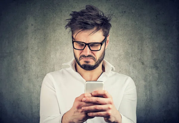 Verärgerter Mann sieht Telefon angewidert an — Stockfoto