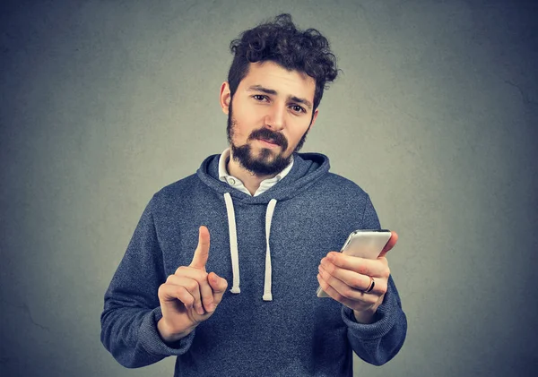 Hombre sosteniendo el teléfono celular mostrando no, atención con el gesto de la mano del dedo — Foto de Stock