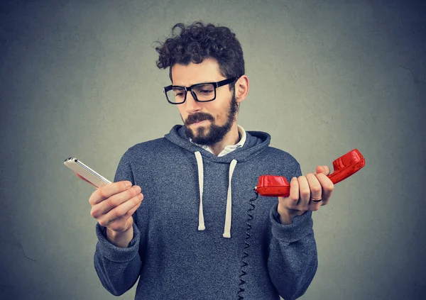 Verwirrter Mann mit alten und neuen Telefonen — Stockfoto