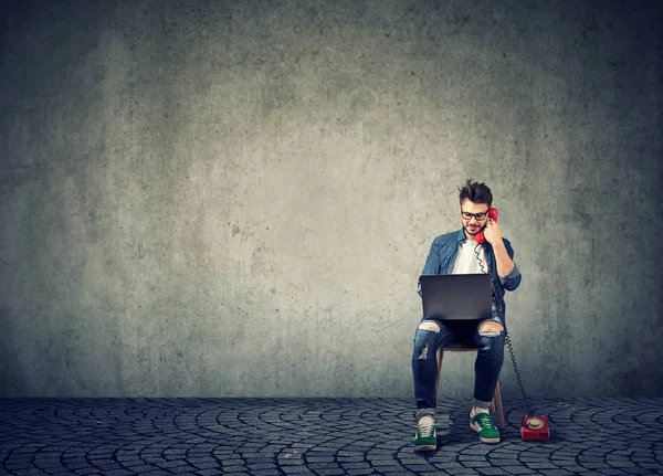 Hipster med laptop och prata på telefon — Stockfoto